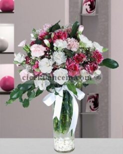 Cam vazoda beyaz, pembe ve kırmızı karanfillerden oluşan bahar esintili aranjman.